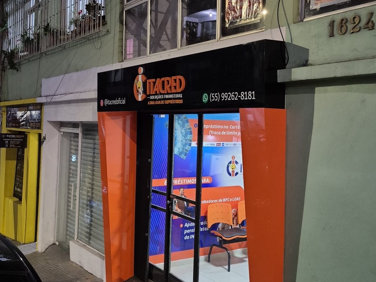 Fachada da Itacred à noite com testeira iluminada e colunas laranja