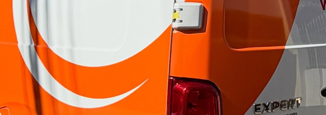Detalhe do vinil laranja aplicado sobre a lataria branca de uma van