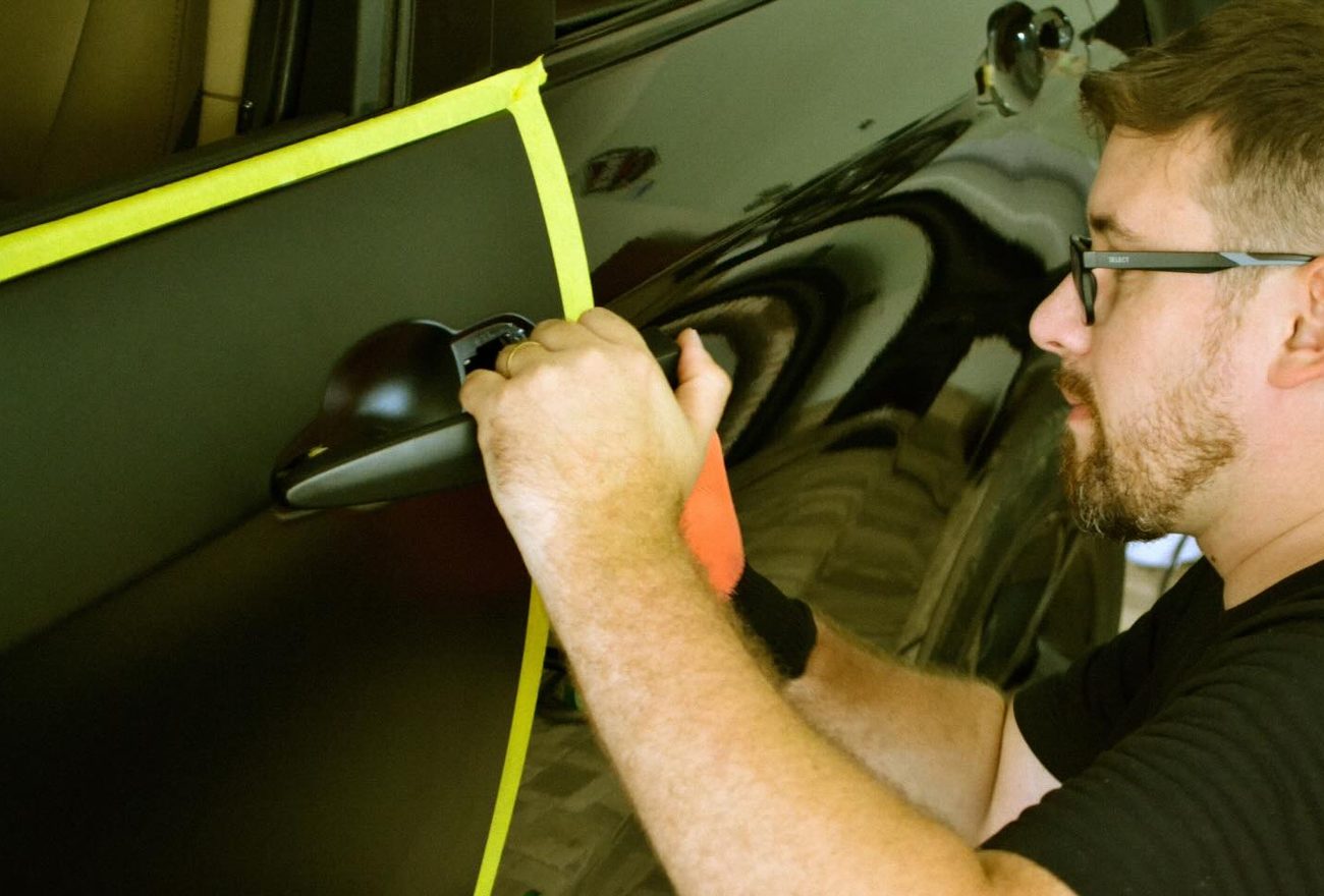 Profissional da Eleva aplicando vinil em veículo com espátula