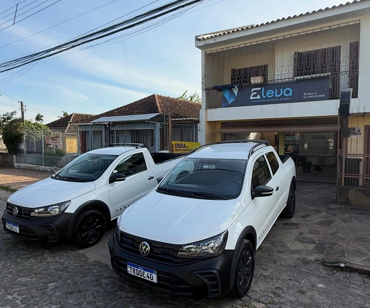 Sede da Eleva com letreiro iluminado e as duas Saveiros da frota estacionadas em frente