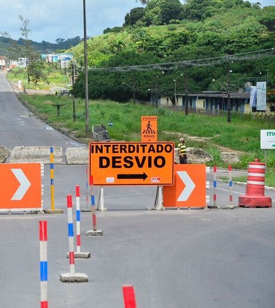 Sinalização viária de obra com placa de interdição e desvio, barreiras e cones na pista